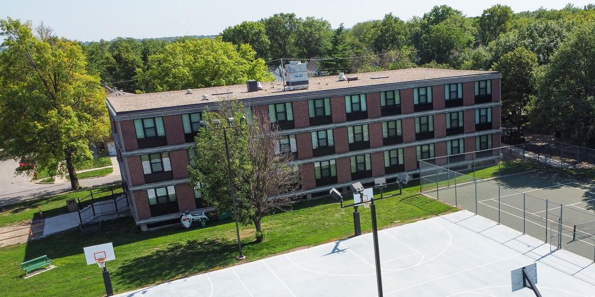 Aerial view of Plainsman Hall with a tennis and basketball court in the foreground.